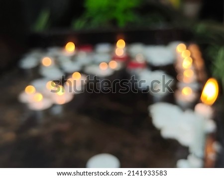 Blurred photo of small firing candles in catholic church on dark background  