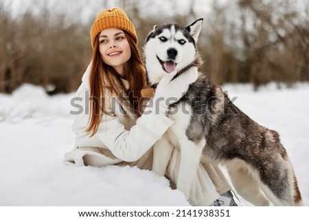 Happy young woman winter clothes walking the dog in the snow winter holidays
