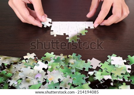 Hand holding puzzle piece on wooden table background