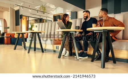 Team of businesspeople working in an office lobby. Three happy businesspeople smiling while having a discussion. Group of modern entrepreneurs collaborating on a new project in a co-working space. Royalty-Free Stock Photo #2141946573