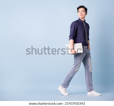 Full length image of young Asian businessman on blue background Royalty-Free Stock Photo #2141950343