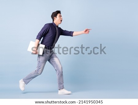 Full length image of young Asian businessman on blue background Royalty-Free Stock Photo #2141950345