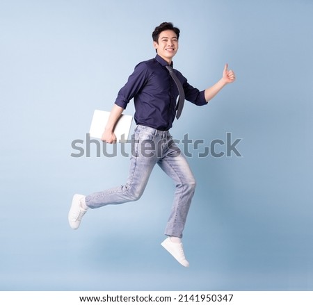 Full length image of young Asian businessman on blue background Royalty-Free Stock Photo #2141950347