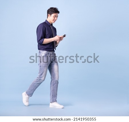 Full length image of young Asian businessman on blue background Royalty-Free Stock Photo #2141950355