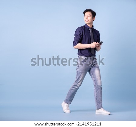 Full length image of young Asian businessman on blue background Royalty-Free Stock Photo #2141951211