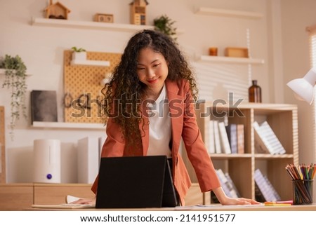 Asian Designer woman work from home and communicate with the design team over the internet. On a tablet,women are having a video conference call.
