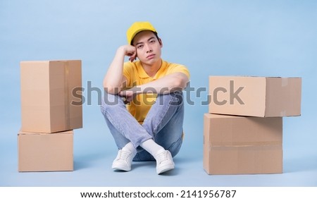 Image of young Asian delivery man on blue background