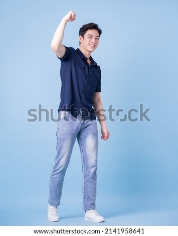 Full length image of young Asian man posing on blue background Royalty-Free Stock Photo #2141958641