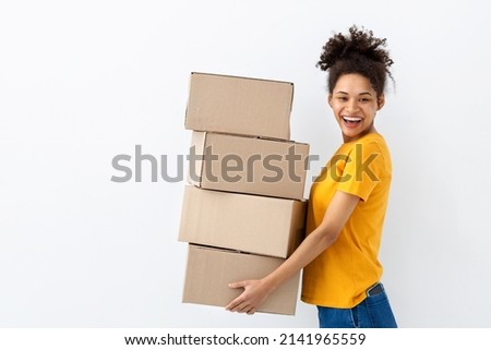 Young happy African American woman with stack of cardboard boxes on white background. Copy spa