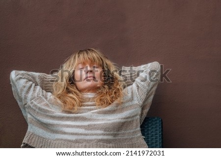 middle-aged woman resting relaxed on the terrace sofa