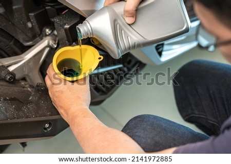 motorcycle mechanic pouring oil into engine scooter at garage  . maintenance and repiar motorcycle concept Royalty-Free Stock Photo #2141972885
