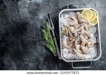 Raw pacific white shrimp prawn peeled with tail on ice. Black background. Top view. Copy space.
