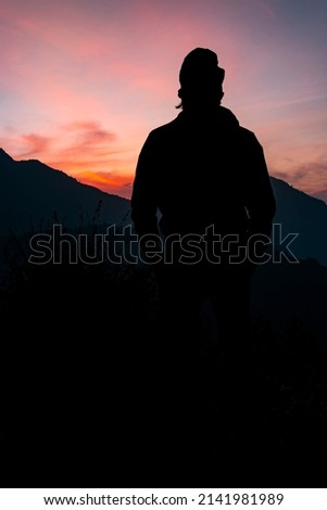 Young man silhouette stay on a mountain top, travel and tourism concept image