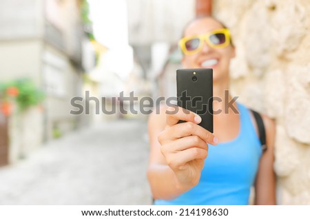 Tourist in yellow glass smile and taking selfie. Focus on phone.