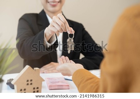 Asian agent giving a key to new owner or tenant, client after signed signature contract rental purchase, buyer apartment, home with landlord, realtor. Banker agreement mortgage loan. Property lease.