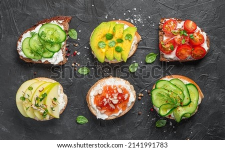Vegetable and fruit crostini on a black background. Bruschetta with feta, ricotta and various additives. Vegetarian sandwiches Top view. Royalty-Free Stock Photo #2141991783