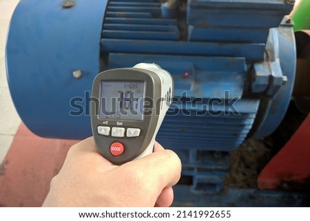 Measuring the temperature of the electric motor using an infrared pyrometer. Part of the image is blurred.