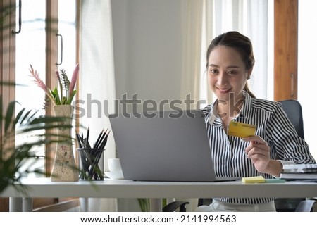 Charming woman holding credit card and shopping online on laptop computer.