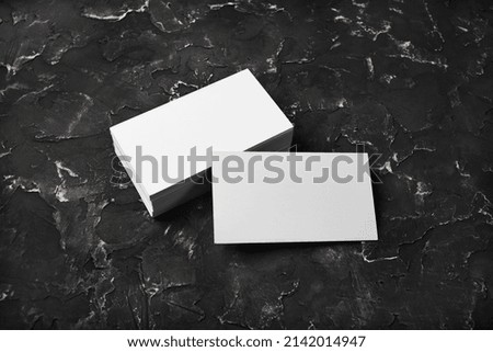 Blank white business cards on black plaster background. Mockup for branding identity.