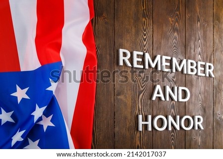 words remember and honor laid with silver metal letters on wooden background with USA flag on the left side in linear perspective