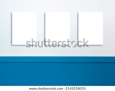 Three mockup empty blank white vertical rectangle border frame with same size hanging on the white and blue wall background . Mock-up poster, picture, photo frames.