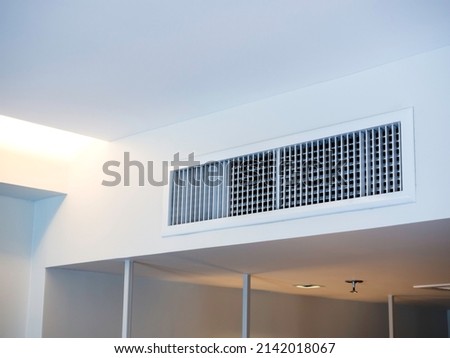 Air conditioning wall mounted ventilation system on ceiling in the white hotel room. Hotel room air ventilation grill on the wall. Royalty-Free Stock Photo #2142018067
