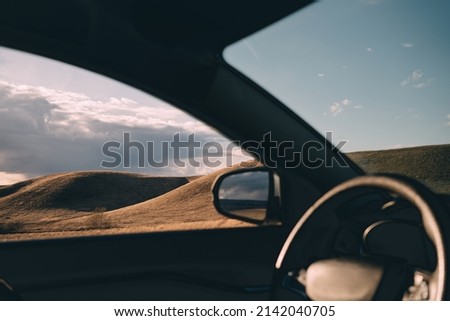 view of the hills from the interior of the car.landscape and tourism concept.spring hills without greenery.cloudy weather in the sky.travel concept.horizontal banner with car relay and mirror
