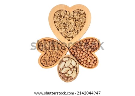 Variety of nuts in wooden cups in the shape of a heart isolated on a white background.