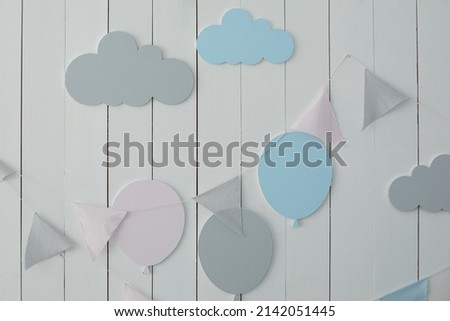 Decoration for baby room. Baby shower party. Kid Holiday. White wall is decorated with multi-colored garland of flags and air ballons. Decor for holiday. Stylish child room with hanging cotton flags. 