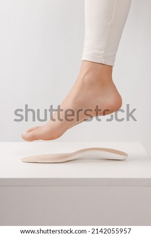 Medical insoles. Isolated orthopedic insoles on a white background. Treatment and prevention of flat feet and foot diseases. Foot care. Insole cutaway layers. Leg hanging over the insole. Royalty-Free Stock Photo #2142055957