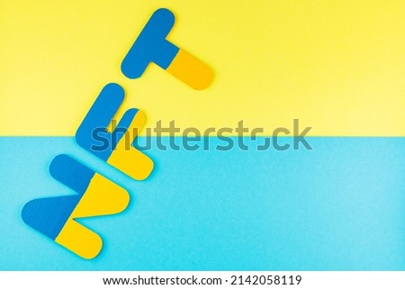 NFT inscription on a blue-yellow background. Non-fungible token in colors of Ukrainian flag. Ukrainian crypto art concept. Top view. Copy space