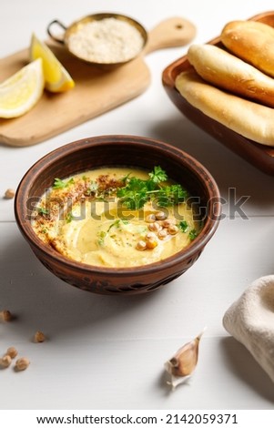 Chickpea or pea paste. Hummus and pita in bowls on a light wooden table. Vertical frame, close-up. Royalty-Free Stock Photo #2142059371
