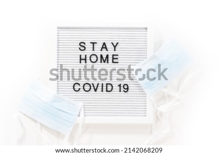 STAY HOME and COVID-19 sign on message board with a blue medical mask.