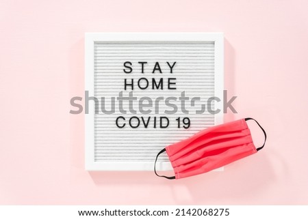 STAY HOME and COVID-19 sign on message board with a homemade face mask.