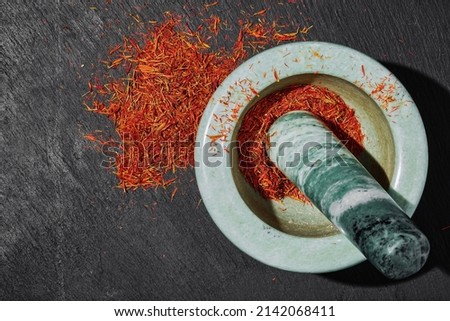 Saffron in a marble mortar on a dark stone background, top view, seasoning preparation. Aromatic spices and seasonings