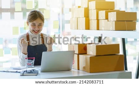 Attractive Asian SME business women use laptop computer checking customer order online shipping boxes at home.