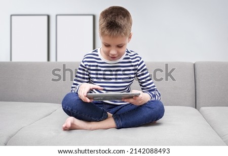 The child holds a gadget in his hands.