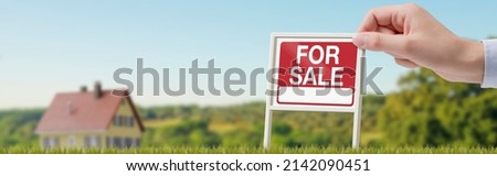 Real estate agent holding a sign and property for sale