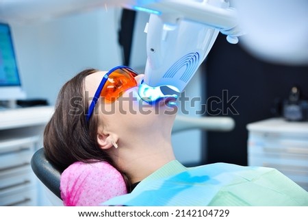Teeth whitening for patient in protective glasses. Laser bleaching teeth in modern clinic. Whitening of teeth at dentist clinic. Royalty-Free Stock Photo #2142104729
