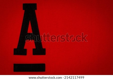 Letter A. Alphabet letter A application and blank label tag made from black material on red fabric background