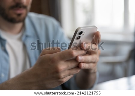 Millennial Caucasian man sitting at table, holding cellphone, typing online chat message on mobile phone. Close up of hands. Guy, business man, office employee making call, browsing on social network Royalty-Free Stock Photo #2142121755