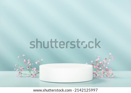 Abstract empty white podium with geometric shadows and pink flowers on blue background. Mock up stand for product presentation. 3D Render. Minimal concept. Advertising template Royalty-Free Stock Photo #2142125997