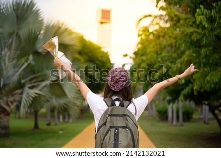 Asian hipster young girl backpack tourist hand holding a map for search and plan her tour.Woman traveler in the park searching road to hotel on map in a foreign city during vacation.