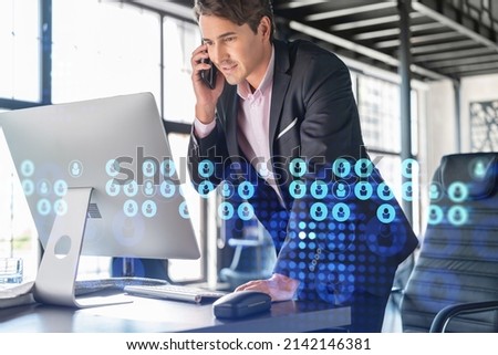 Businessman in suit has conference call to hire new employees for international business consulting. HR, social media hologram icons and interconnections over office background with panoramic windows Royalty-Free Stock Photo #2142146381