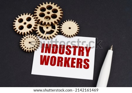 Industrial concept. On the black surface are gears, a pen and a business card with the inscription - Industry Workers