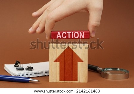 Business concept. On a brown surface are office items, wooden blocks, in the hand is a red block with the inscription - ACTION Royalty-Free Stock Photo #2142161483