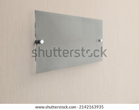 Wide rectangle gray glass nameplate plate on spacer metal holders. Clear printing board for branding. Acrilic advertising signboard on white background mock-up side view. proportional 1 to 2.