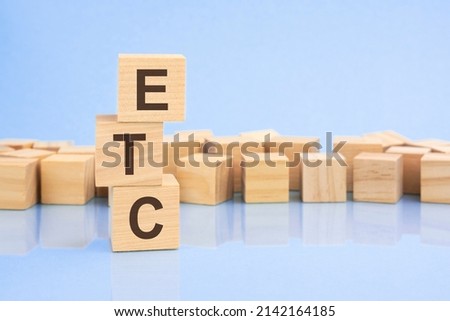on a bright pale lilac and blue background, light wooden blocks and cubes with the text ETC. cubes is reflected from the surface. ETC - short for electronic trade confirmation or et cetera Royalty-Free Stock Photo #2142164185