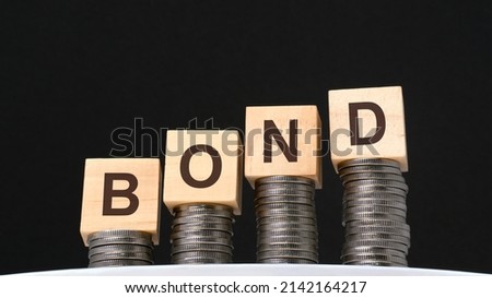 on a black background are coins and wooden cubes with the inscription - bond, business and economy concept.