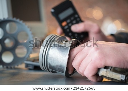 Worker is calculating the price of car spare parts with calculator concept. Car repair cost estimate.